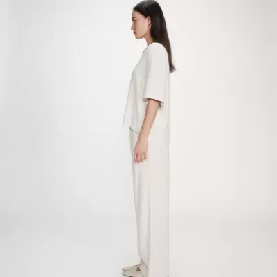 Mulher a usar roupa bege clara em fundo branco