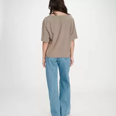 Mulher de costas com t-shirt bege e calças largas de ganga azul claro