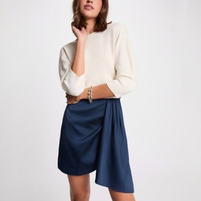 Mulher vestindo vestido preto de malha com parte inferior azul-escuro e botas pretas