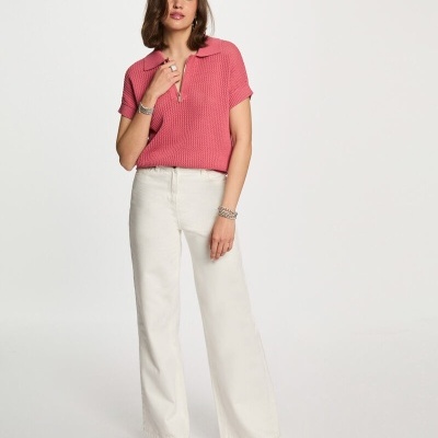 mulher com blusa rosa de malha e calças largas brancas