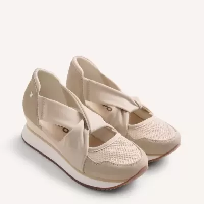 Ténis desportivos bege com faixa cruzada em fundo neutro