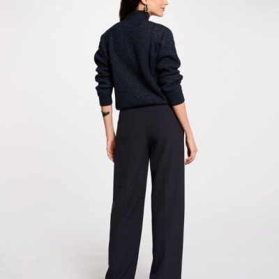 Mulher vista de costas com calças azuis e camisola azul escura de gola alta