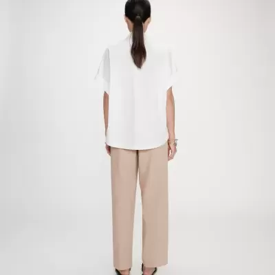 Pessoa de costas vestindo camisa branca e calças bege