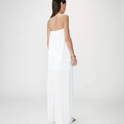 Mulher vista de costas com macacão branco plissado sem alças