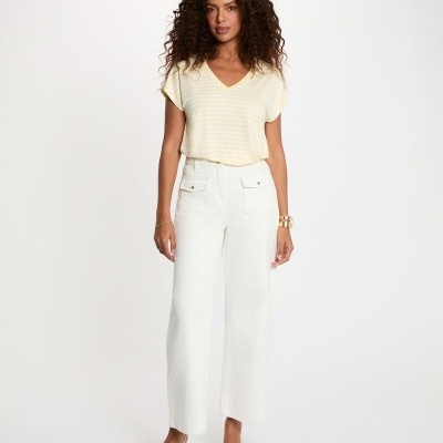 Mulher com blusa amarela de riscas e calças brancas largas