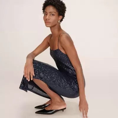 Mulher vestindo vestido azul escuro com lantejoulas e sapatos pretos