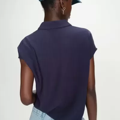 Pessoa de costas com top azul escuro, jeans claros e boné de ganga azul.