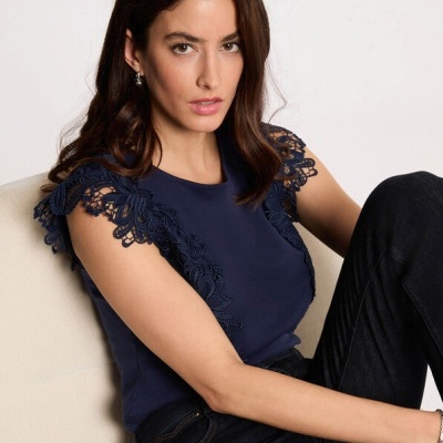 T-shirt azul escura com renda nas mangas em mulher sentada