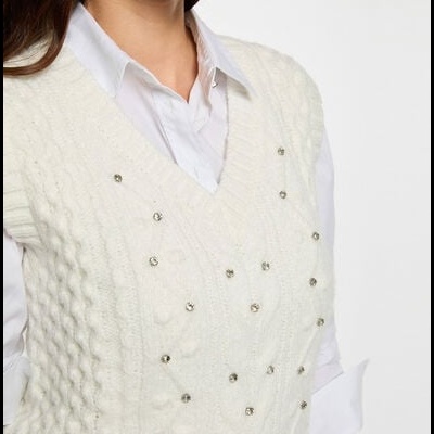Colete de malha branco com aplicações de contas prateadas por cima de camisa branca