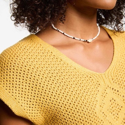 Blusa amarela de malha com padrão de pontos abertos e decote em V