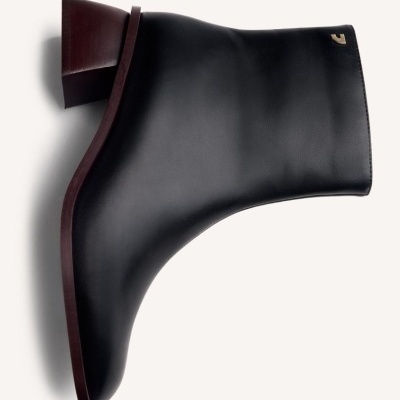 Bota preta de salto médio em pele lisa com solado castanho e logotipo dourado