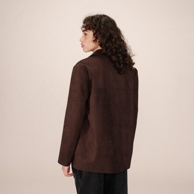 Casaco castanho escuro visto de costas, usado por mulher com cabelo encaracolado e calças pretas largas.