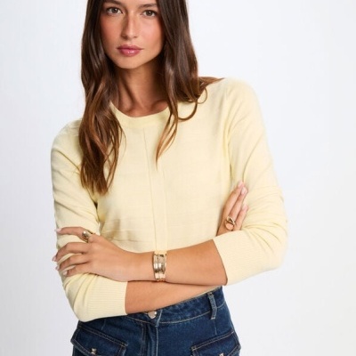 Mulher a usar camisola amarela de malha fina e calças de ganga azul escuro com bolsos