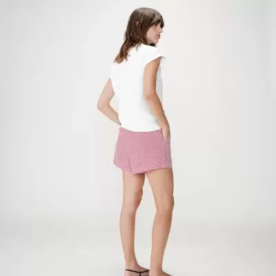 Mulher de costas com t-shirt branca e calção curto xadrez vermelho e branco