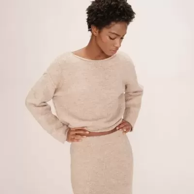 Mulher com conjunto bege de camisola de manga comprida e saia comprida em malha felpuda