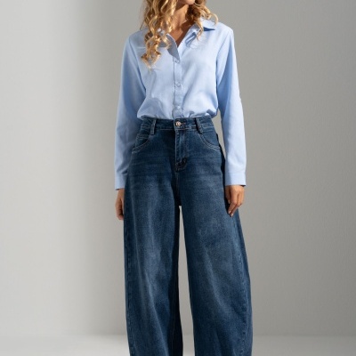 Mulher com camisa azul clara e calças largas de ganga azuis