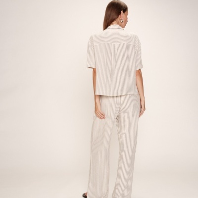Conjunto feminino creme às riscas visto de costas com fundo neutro