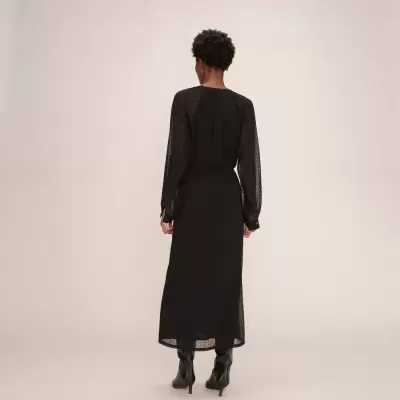 Mulher vista de costas vestindo vestido preto de pontos e botas pretas