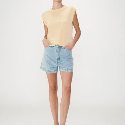 Mulher com camisola castanha clara, calções de ganga azul e sandálias pretas