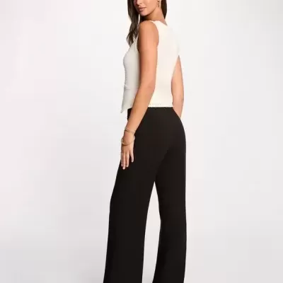 Mulher com top branco e calças pretas largas