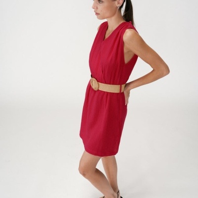 Mulher vestindo vestido vermelho com cinto bege e sandálias pretas em fundo branco