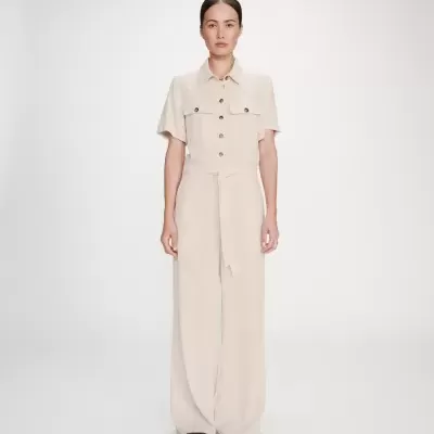 Macacão comprido bege claro com botões, cinto, duas peitorais e sapatos pretos