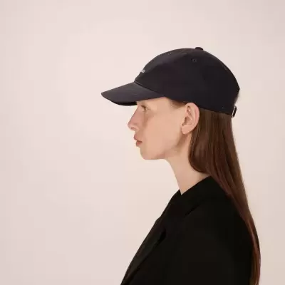 Mulher de perfil com boné preto e casaco preto