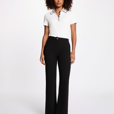 Mulher com blusa branca de gola e calças pretas flare com botins pretos