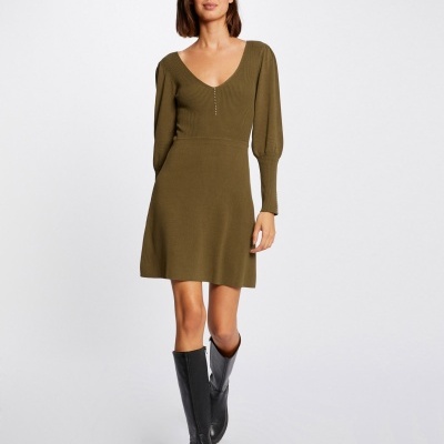 Vestido verde-oliva de malha com mangas compridas usado com botas pretas.