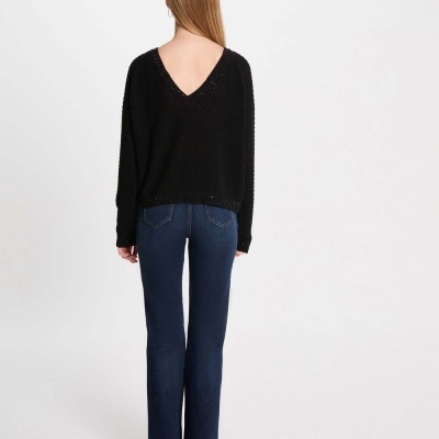 Mulher de costas com suéter preto de malha e calças de ganga azul escuras