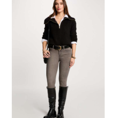 Mulher com camisola preta, calças cinza, botas pretas e bolsa preta