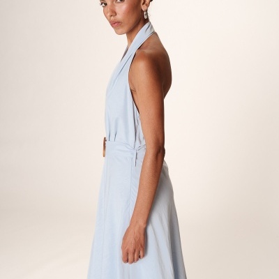 Vestido azul claro com cinto em modelo feminino de lado, fundo claro