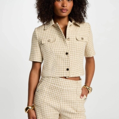 Conjunto feminino bege e branco em padrão pied-de-poule com camisa curta e calções, modelo com pulseiras douradas.