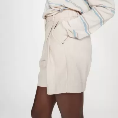 Calções bege claro com bolsos usados por pessoa com camisola riscada