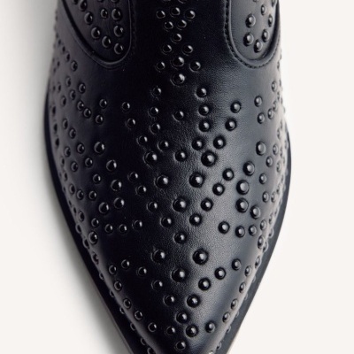 Sapato preto de pele com rebites redondos pretos em padrão, vista aérea da ponta.