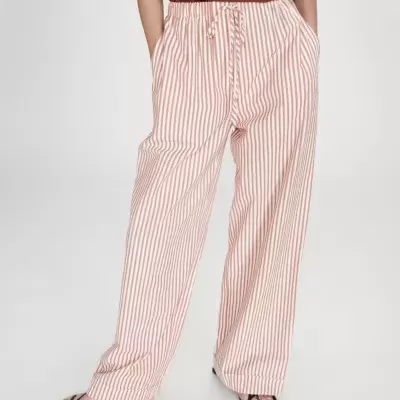 Calças largas às riscas brancas e vermelhas com sandálias pretas.