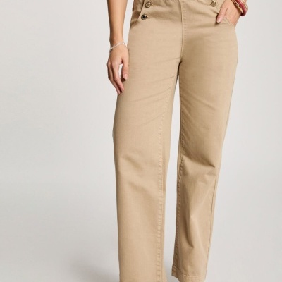 Calças bejes de tecido com botões decorativos e botas castanhas.