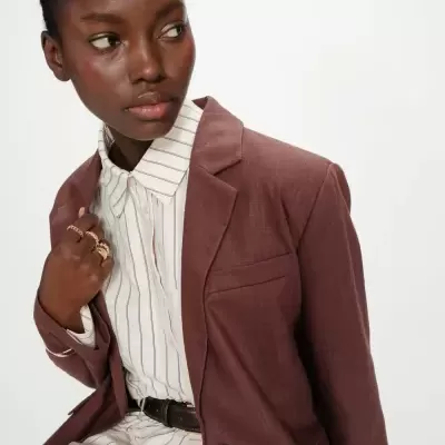 Blazer castanho avermelhado com camisa creme riscada e cinto preto em fundo branco