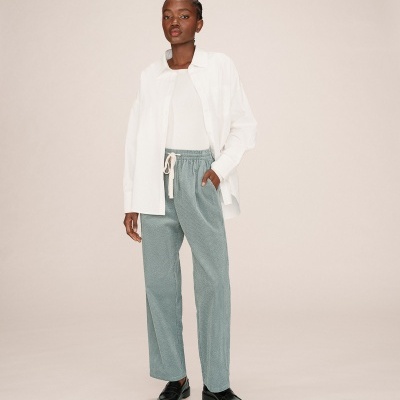 Modelo a usar calças verdes água com cintura elástica e camisa branca oversize.