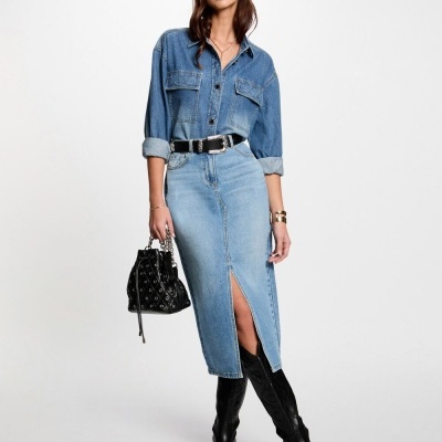 Mulher com conjunto de roupa de ganga azul e botas pretas em fundo branco