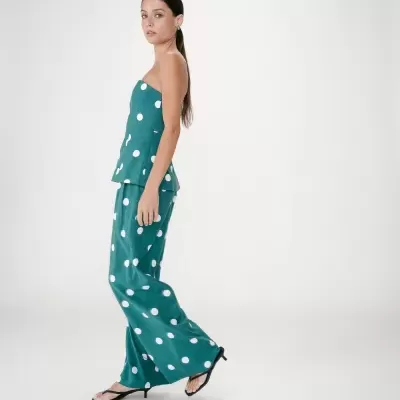 Conjunto feminino sem alças verde com bolinhas brancas e sandálias pretas de salto fino.