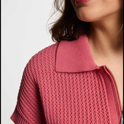 Peça de vestuário em malha rosa com textura perfurada e fecho de correr