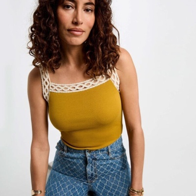 Top amarelo mostarda com alças de renda e jeans azuis com padrão xadrez