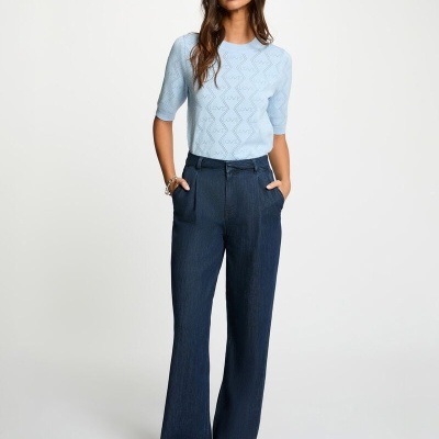 Mulher com camisola azul clara e calças largas de ganga azul escuro