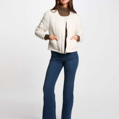 Modelo a usar casaco acolchoado branco e jeans azuis em fundo branco