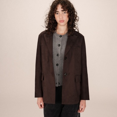 Mulher com casaco castanho escuro liso e camisola cinza com botões pretos