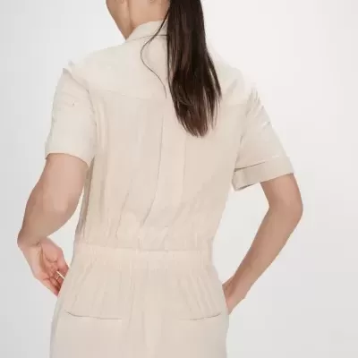 Macacão curto bege claro visto de costas com elástico na cintura e bolsos traseiros