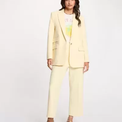 Conjunto feminino amarelo claro com blazer, calças pantalonas, t-shirt branca com estampa e sandálias de salto