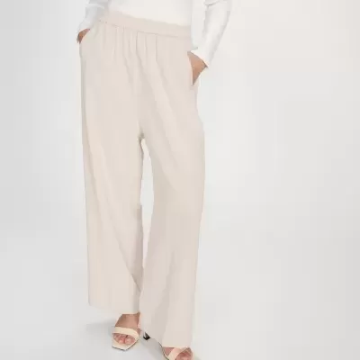 Calças largas bege claro com cós elástico e sandálias bege em fundo branco