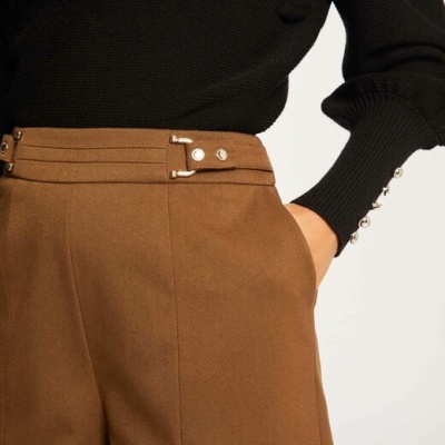 Calças castanhas com cinto e camisola preta de mangas compridas com botões